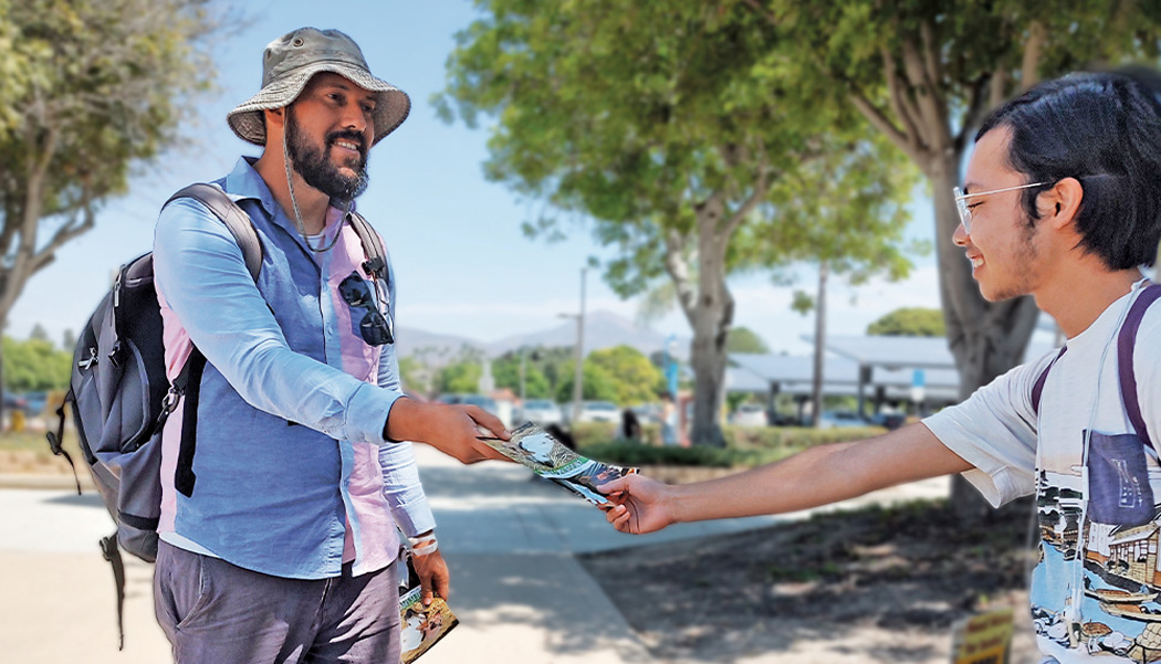 Adopt A College, Brian Chavez handing a student a booklet