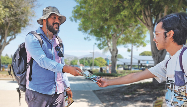 Adopt A College, Brian Chavez handing a student a booklet